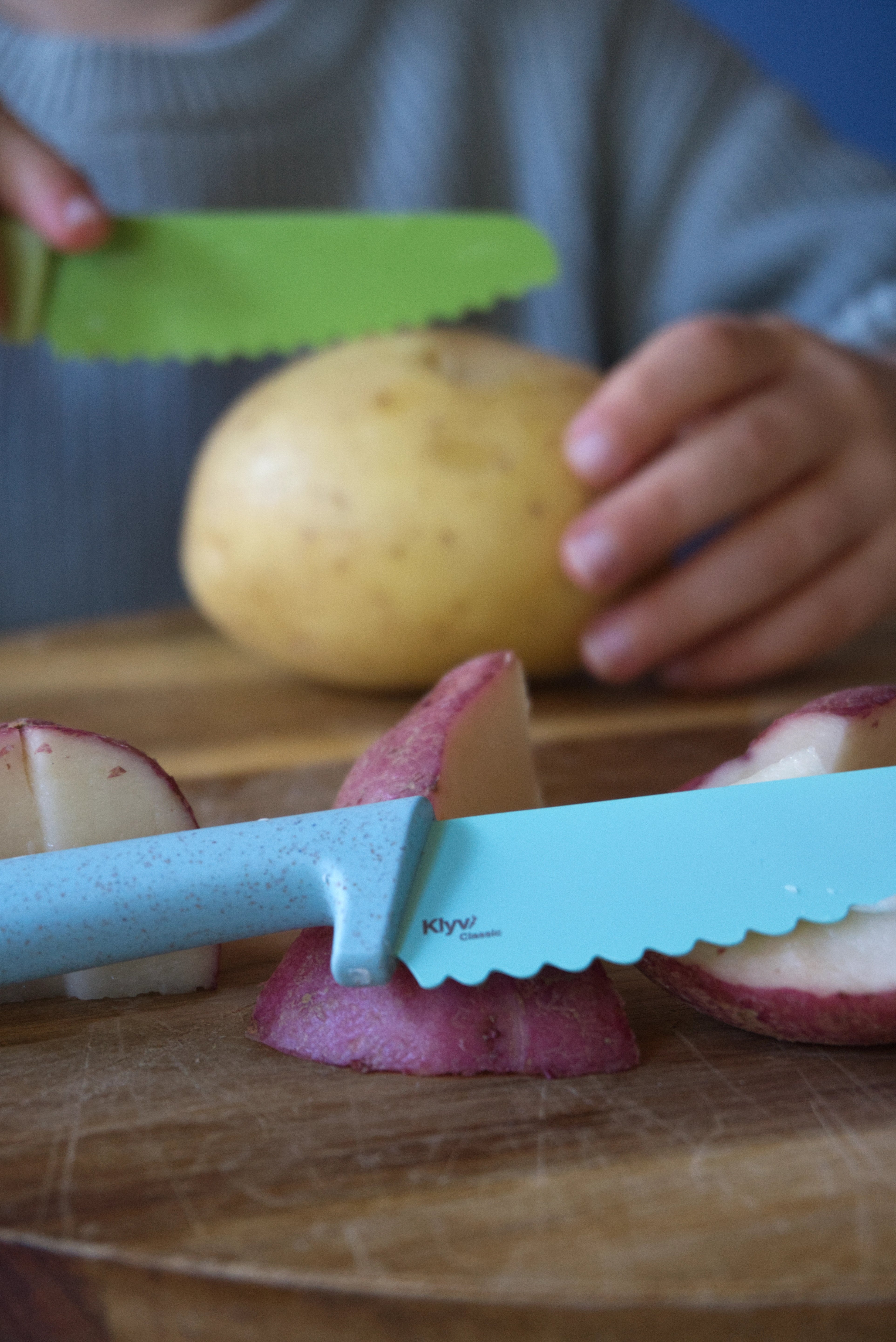 Kid children cutting potatoes with a blue knife on a wooden cutting board, Klyv classic knife for 3 years old Aqua Scandinavian Design Lime