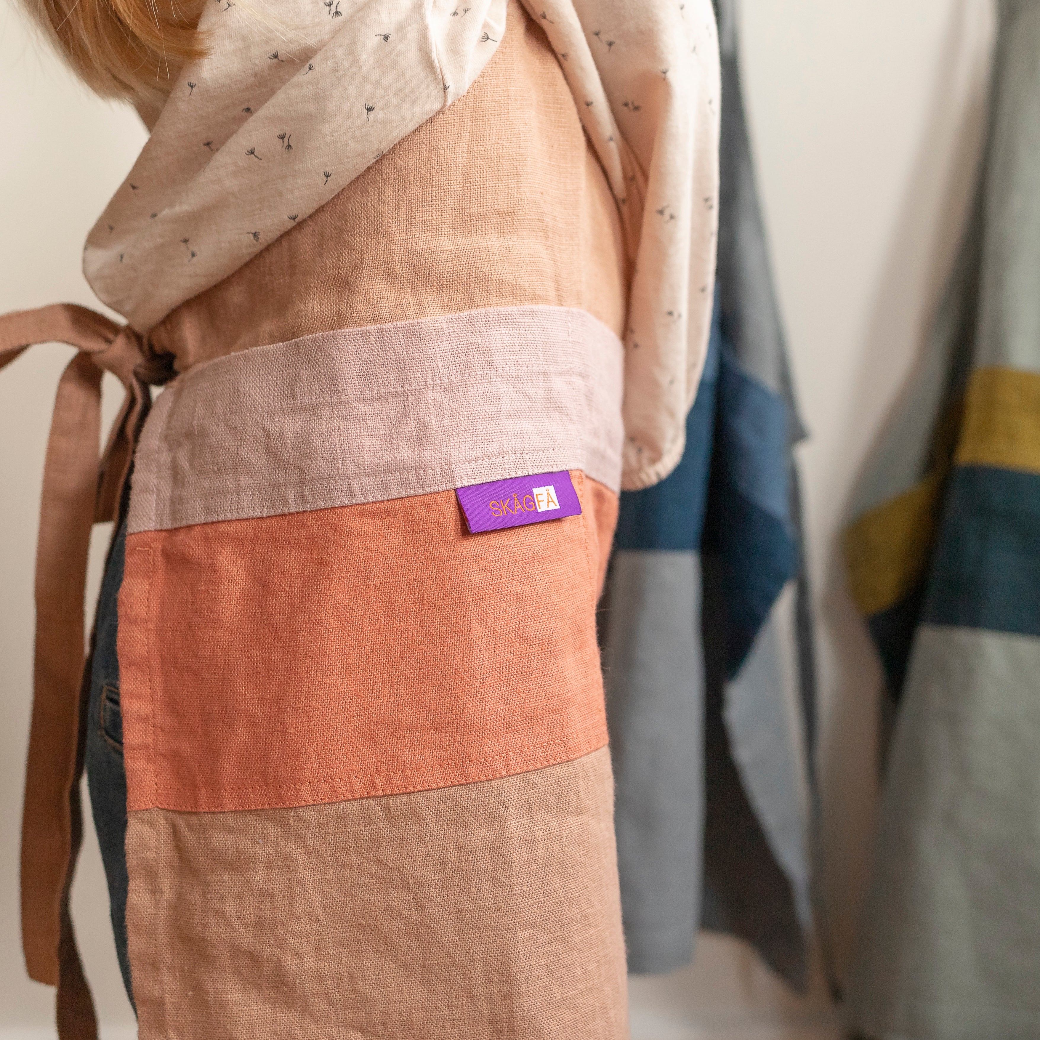 Young chef in a minimalist kitchen sporting 'The Förkläde' linen chef apron by SKÅGFÄ, reflecting Scandinavian design principles with its clean lines and functional features like an adjustable neck strap and deep pockets. Crafted in Europe from 100% OEKO-TEX certified stone-washed linen, this apron combines durability, sustainability, and a timeless aesthetic, ideal for children's culinary explorations.
